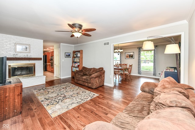 3012 Rollshore Ct, Carmel, IN 46033 - living room with ceiling fan, a brick fireplace, wood finished floors, ornamental molding, and a chandelier