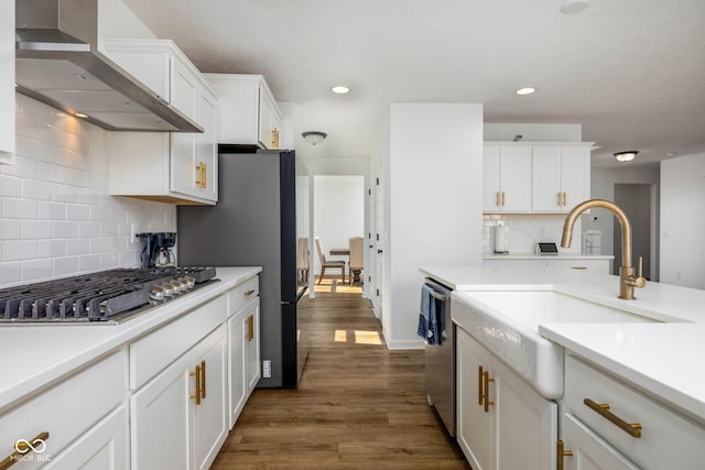 10524 Broadford St, Indianapolis, IN 46239 - kitchen featuring wall chimney exhaust hood, appliances with stainless steel finishes, white cabinets, dark wood-style flooring, and light countertops