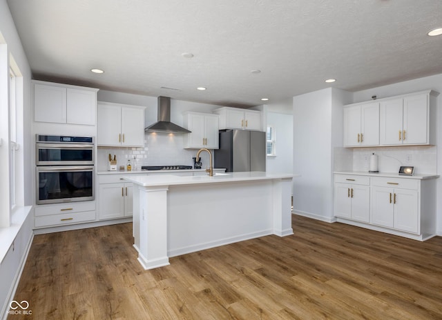 10524 Broadford St, Indianapolis, IN 46239 - kitchen featuring wall chimney exhaust hood, appliances with stainless steel finishes, backsplash, dark wood-type flooring, and light countertops