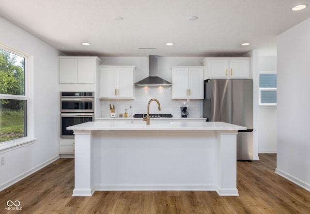 10524 Broadford St, Indianapolis, IN 46239 - kitchen featuring wall chimney range hood, appliances with stainless steel finishes, light countertops, a center island with sink, and tasteful backsplash