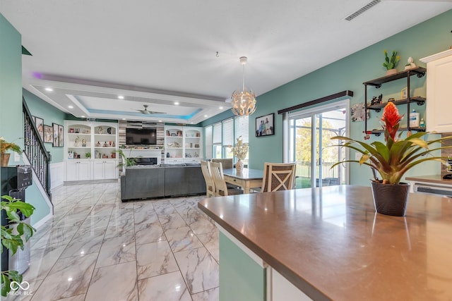 1358 Avocet Dr, Greenwood, IN 46143 - dining space with a tray ceiling, a ceiling fan, light marble finish flooring, a chandelier, and a large fireplace