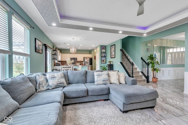 1358 Avocet Dr, Greenwood, IN 46143 - living room featuring a tray ceiling, stairway, recessed lighting, a chandelier, and light marble finish floors