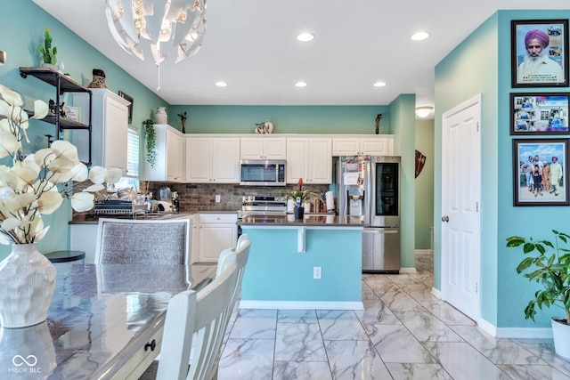 1358 Avocet Dr, Greenwood, IN 46143 - kitchen with appliances with stainless steel finishes, a chandelier, white cabinetry, light marble finish floors, and a kitchen island
