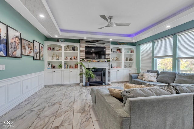 1358 Avocet Dr, Greenwood, IN 46143 - living room with a raised ceiling, a ceiling fan, a large fireplace, light marble finish floors, and wainscoting