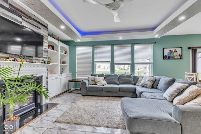 1358 Avocet Dr, Greenwood, IN 46143 - living area featuring a tray ceiling, a fireplace, light marble finish flooring, ceiling fan, and built in features