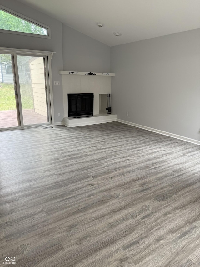 4024 Zinfandel Way, Indianapolis, IN 46254 - unfurnished living room with wood finished floors, a tile fireplace, and lofted ceiling