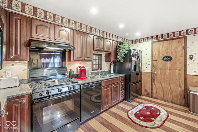 6241 S Meridian St, Indianapolis, IN 46217 - kitchen featuring black appliances, under cabinet range hood, light wood-style flooring, wainscoting, and wallpapered walls