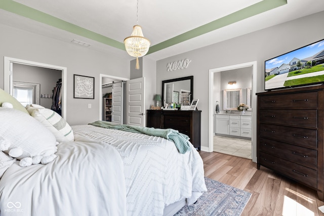 19677 Sumrall Pl, Westfield, IN 46074 - bedroom with a spacious closet, light wood-type flooring, ensuite bathroom, and a chandelier