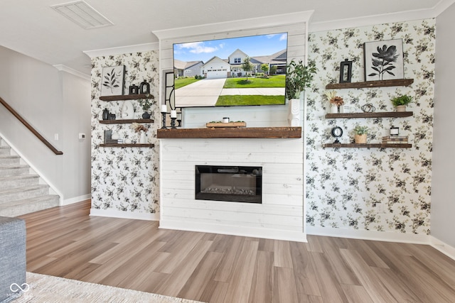 19677 Sumrall Pl, Westfield, IN 46074 - unfurnished living room featuring wood finished floors, crown molding, stairway, a glass covered fireplace, and wallpapered walls