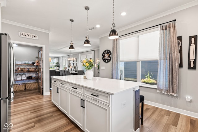 19677 Sumrall Pl, Westfield, IN 46074 - kitchen with freestanding refrigerator, white cabinetry, light wood-type flooring, a breakfast bar area, and a kitchen island