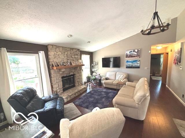 11 Mccutcheon Dr, Lafayette, IN 47909 - living room featuring a textured ceiling, lofted ceiling, wood finished floors, a stone fireplace, and a chandelier