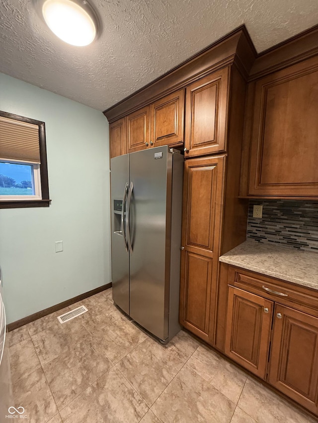 11698 N Bethesda Rd, Mooresville, IN 46158 - kitchen featuring stainless steel fridge with ice dispenser, decorative backsplash, a textured ceiling, and brown cabinetry