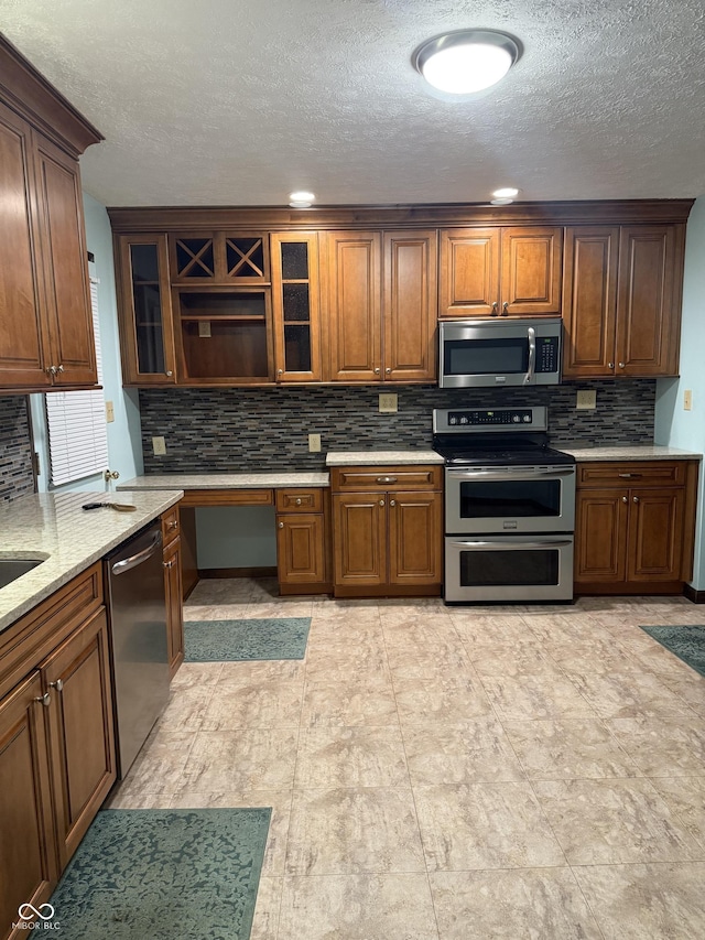 11698 N Bethesda Rd, Mooresville, IN 46158 - kitchen featuring stainless steel appliances, decorative backsplash, a textured ceiling, glass insert cabinets, and brown cabinetry