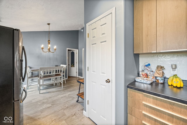 3914 Chenango Pl, West Lafayette, IN 47906 - kitchen featuring freestanding refrigerator, a chandelier, a textured ceiling, tasteful backsplash, and pendant lighting