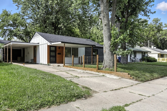 8138 Harrison Dr, Lawrence, IN 46226 - view of front of property featuring board and batten siding, a front yard, driveway, a carport, and roof with shingles