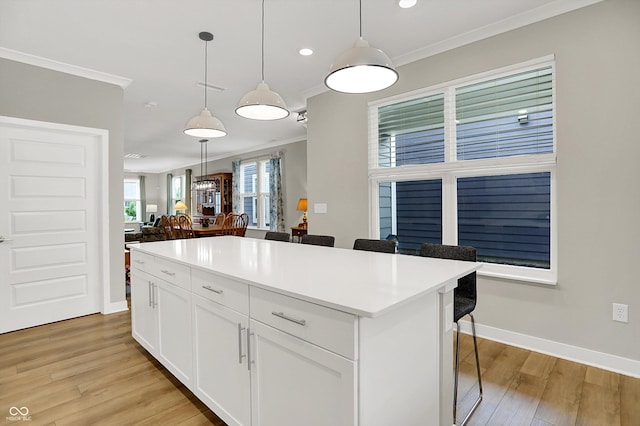 355 Ehrlich Ln, Westfield, IN 46074 - kitchen with ornamental molding, a breakfast bar, light wood-type flooring, a kitchen island, and white cabinetry