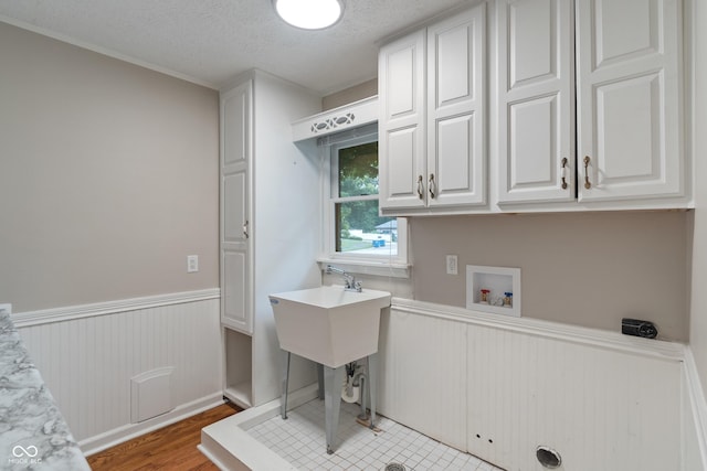 10184 Lakeshore Dr E, Carmel, IN 46033 - laundry room with a wainscoted wall, hookup for a washing machine, cabinet space, light wood-type flooring, and a textured ceiling