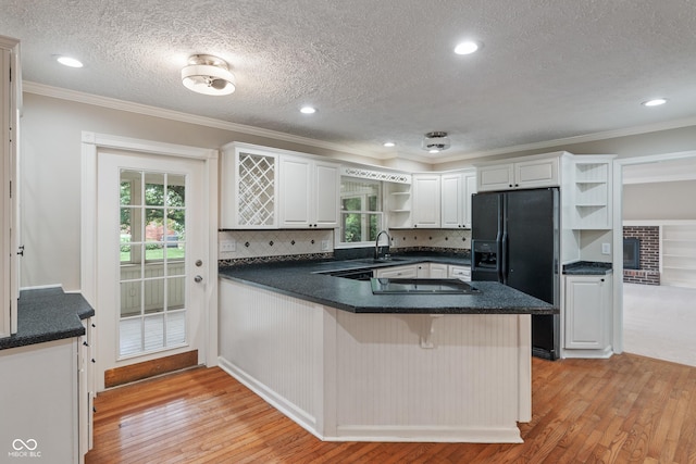 10184 Lakeshore Dr E, Carmel, IN 46033 - kitchen featuring open shelves, black fridge, light wood-style flooring, cooktop, and dark countertops