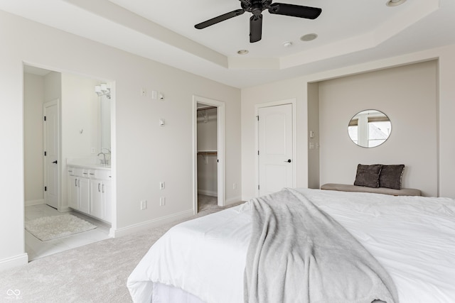 2570 Congress St, Carmel, IN 46032 - bedroom with a tray ceiling, light colored carpet, a walk in closet, connected bathroom, and a ceiling fan