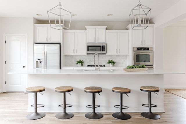 2570 Congress St, Carmel, IN 46032 - kitchen featuring appliances with stainless steel finishes, a chandelier, an island with sink, tasteful backsplash, and light countertops