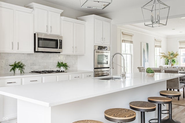 2570 Congress St, Carmel, IN 46032 - kitchen with appliances with stainless steel finishes, a center island with sink, light countertops, tasteful backsplash, and white cabinets