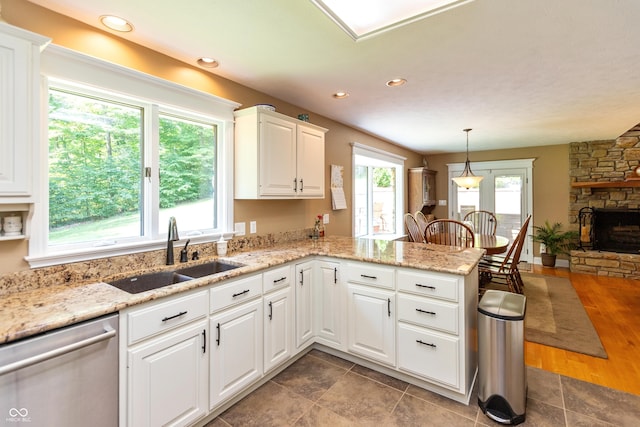 3750 S Whitehorse Rd, Nashville, IN 47448 - kitchen featuring stainless steel dishwasher, a peninsula, white cabinetry, hanging light fixtures, and a stone fireplace