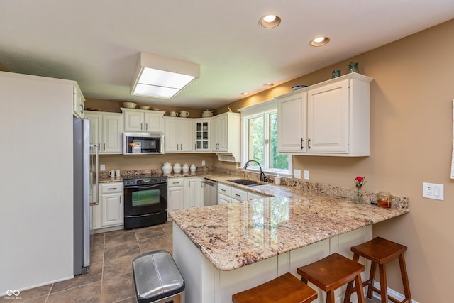3750 S Whitehorse Rd, Nashville, IN 47448 - kitchen with stainless steel appliances, a peninsula, white cabinets, light stone counters, and a kitchen breakfast bar