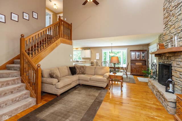 3750 S Whitehorse Rd, Nashville, IN 47448 - living area featuring light wood-type flooring, stairs, a towering ceiling, ceiling fan, and a stone fireplace