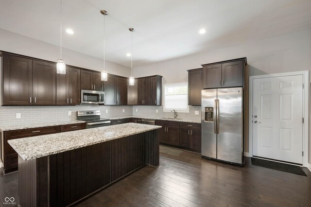 869 N Park Trail Dr, Carmel, IN 46032 - kitchen with stainless steel appliances, dark brown cabinetry, tasteful backsplash, a center island, and decorative light fixtures