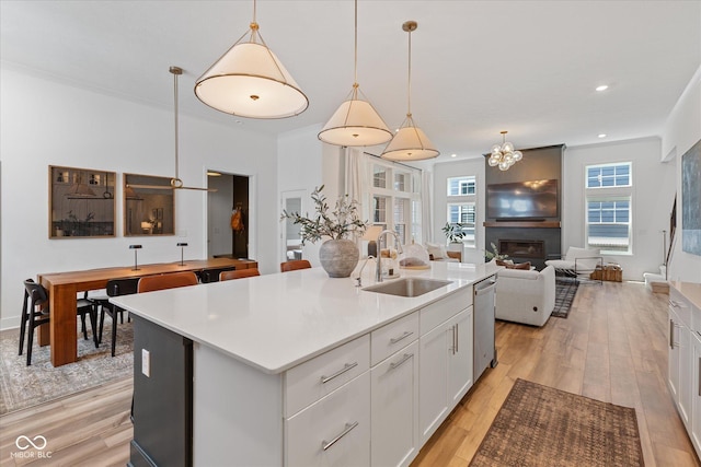 1275 Stonehaven Dr, Westfield, IN 46074 - kitchen with stainless steel dishwasher, light wood-style floors, a kitchen island with sink, white cabinetry, and light countertops