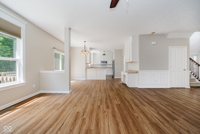 13722 Wendessa Dr, Fishers, IN 46038 - unfurnished living room with light wood finished floors, a ceiling fan, a chandelier, and stairway