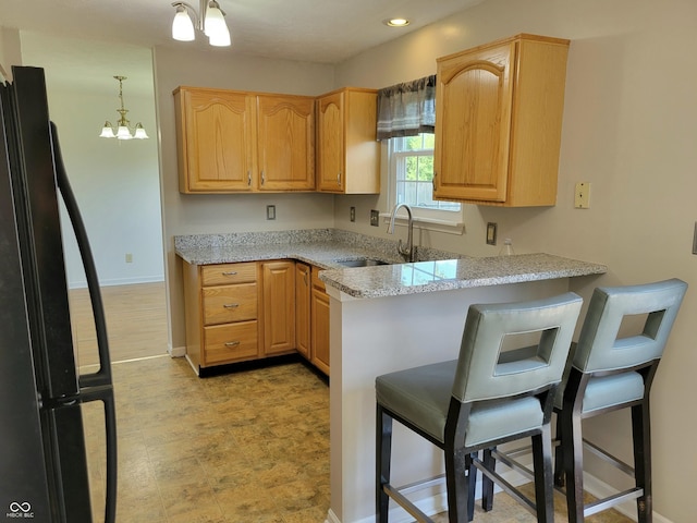1047 S Jefferson St, Brownsburg, IN 46112 - kitchen featuring freestanding refrigerator, a peninsula, light stone countertops, a breakfast bar area, and recessed lighting