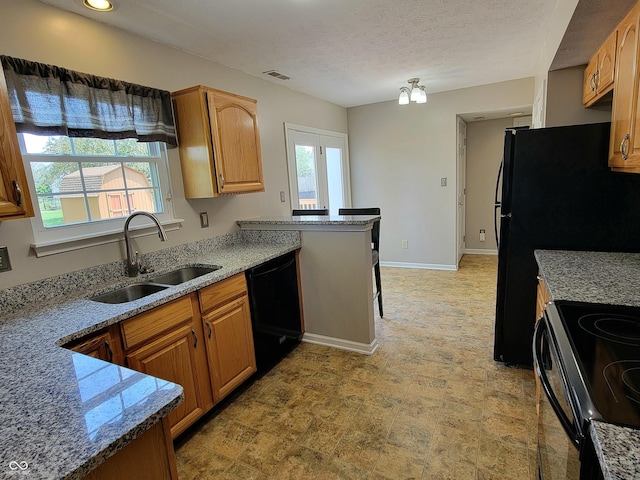 1047 S Jefferson St, Brownsburg, IN 46112 - kitchen featuring black appliances, brown cabinetry, light stone countertops, a peninsula, and a textured ceiling