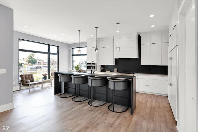 13417 Cambridge Cove Way, Fishers, IN 46055 - kitchen with modern cabinets, a breakfast bar area, an island with sink, tasteful backsplash, and white cabinetry