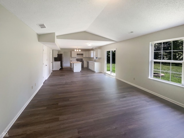81 Brookland Ln, Pittsboro, IN 46167 - unfurnished living room with a textured ceiling, dark wood-type flooring, lofted ceiling, and a chandelier