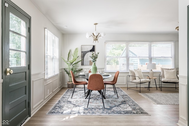 316 Ohmer Ave, Indianapolis, IN 46219 - dining area with plenty of natural light, a decorative wall, a chandelier, light wood-style flooring, and a wainscoted wall