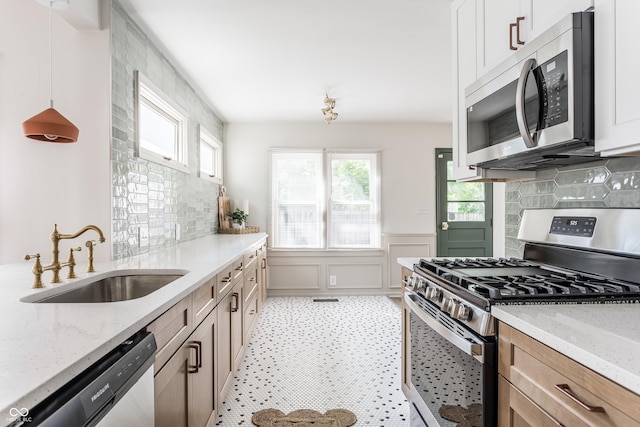 316 Ohmer Ave, Indianapolis, IN 46219 - kitchen with appliances with stainless steel finishes, light stone countertops, decorative backsplash, wainscoting, and a decorative wall