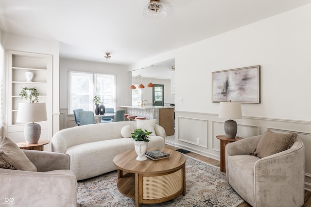 316 Ohmer Ave, Indianapolis, IN 46219 - living area featuring light wood-style flooring, wainscoting, and a decorative wall
