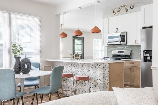 316 Ohmer Ave, Indianapolis, IN 46219 - kitchen with stainless steel appliances, tasteful backsplash, light countertops, decorative light fixtures, and a kitchen island with sink