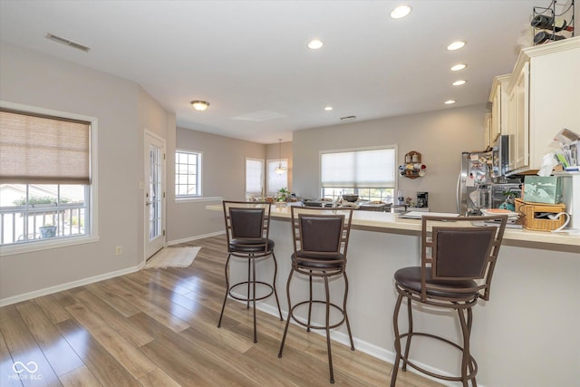 4285 Washington Blvd, Plainfield, IN 46168 - kitchen featuring a breakfast bar, light countertops, light wood-style floors, recessed lighting, and freestanding refrigerator