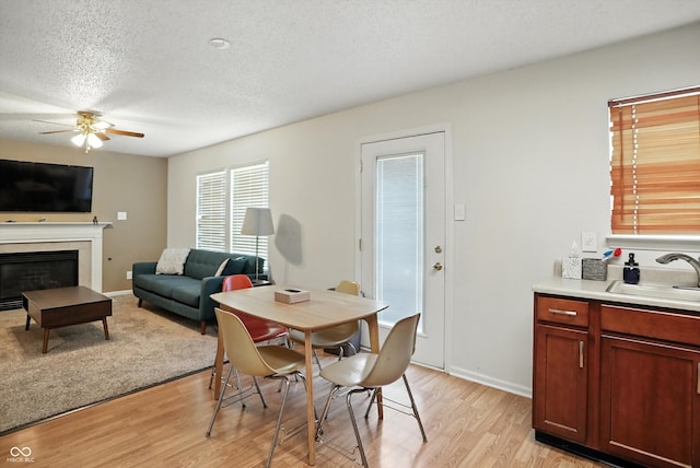2421 Amberleigh Dr, Plainfield, IN 46168 - dining space featuring ceiling fan, a textured ceiling, light wood-type flooring, and a glass covered fireplace