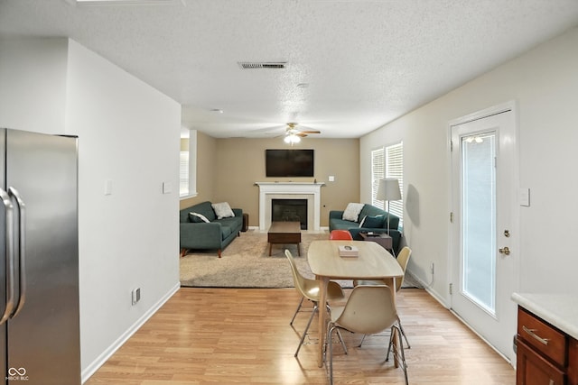 2421 Amberleigh Dr, Plainfield, IN 46168 - dining area with ceiling fan, a glass covered fireplace, light wood-style floors, and a textured ceiling