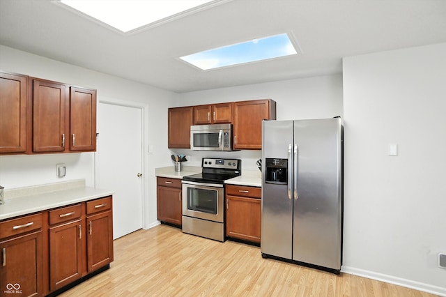 2421 Amberleigh Dr, Plainfield, IN 46168 - kitchen featuring appliances with stainless steel finishes, light wood-type flooring, light countertops, a skylight, and brown cabinets