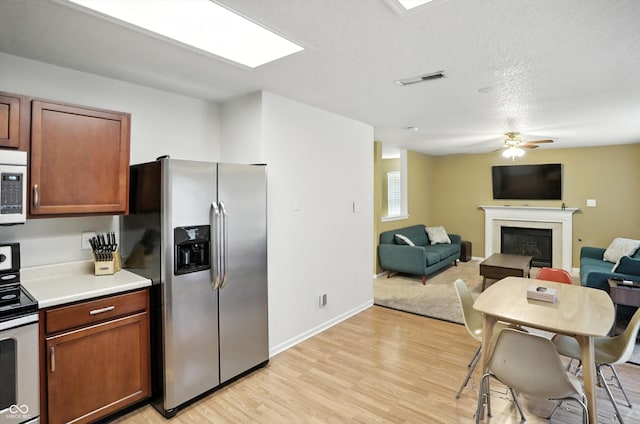 2421 Amberleigh Dr, Plainfield, IN 46168 - kitchen with white appliances, a ceiling fan, a glass covered fireplace, light wood finished floors, and light countertops