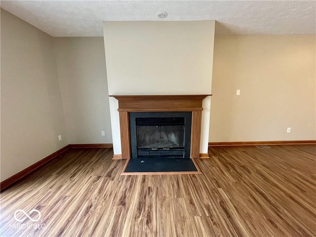 35 Northridge Ct, Brownsburg, IN 46112 - unfurnished living room featuring wood finished floors, a textured ceiling, and a fireplace with flush hearth