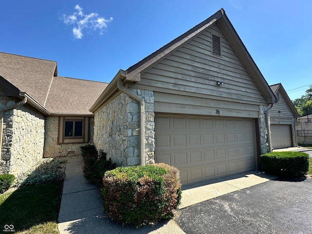 35 Northridge Ct, Brownsburg, IN 46112 - view of side of property with stone siding, an attached garage, roof with shingles, and driveway