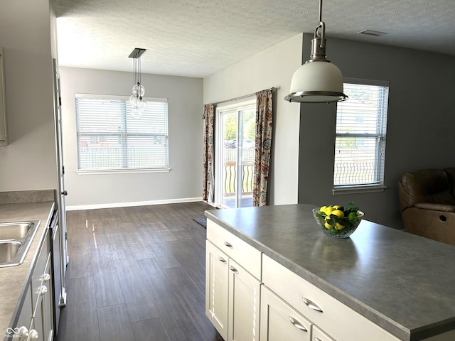 8287 Falkirk Dr, Avon, IN 46123 - kitchen with dark wood finished floors, a textured ceiling, white cabinets, hanging light fixtures, and dark countertops