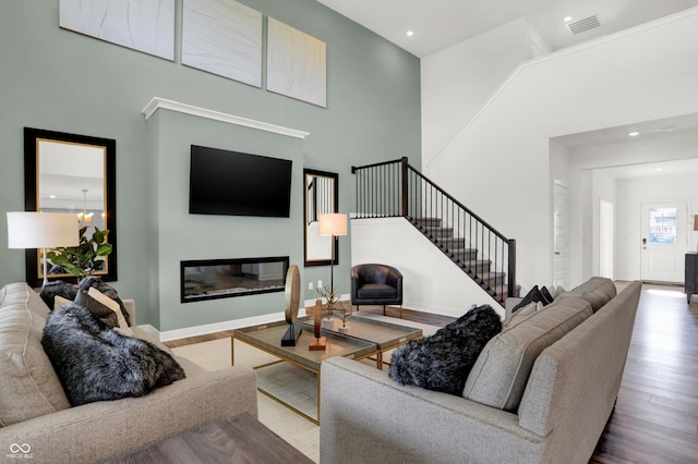 17040 Daly Dr, Noblesville, IN 46062 - living room featuring stairway, wood finished floors, a glass covered fireplace, recessed lighting, and a towering ceiling