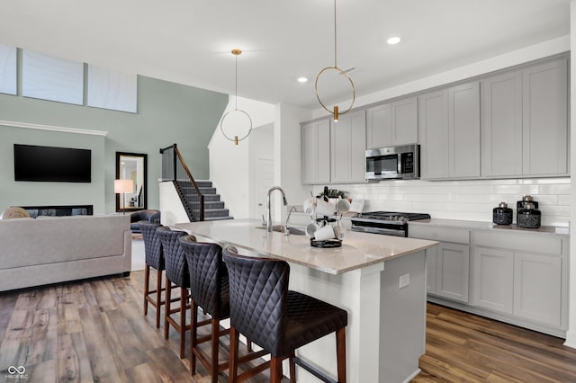 17040 Daly Dr, Noblesville, IN 46062 - kitchen featuring stainless steel microwave, range with gas stovetop, backsplash, a breakfast bar, and gray cabinetry