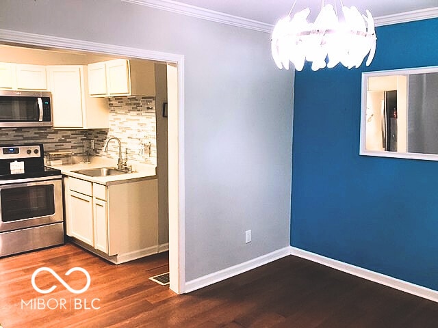 2419 Mars Hill St, Indianapolis, IN 46241 - kitchen featuring stainless steel appliances, crown molding, backsplash, dark wood-style floors, and a chandelier